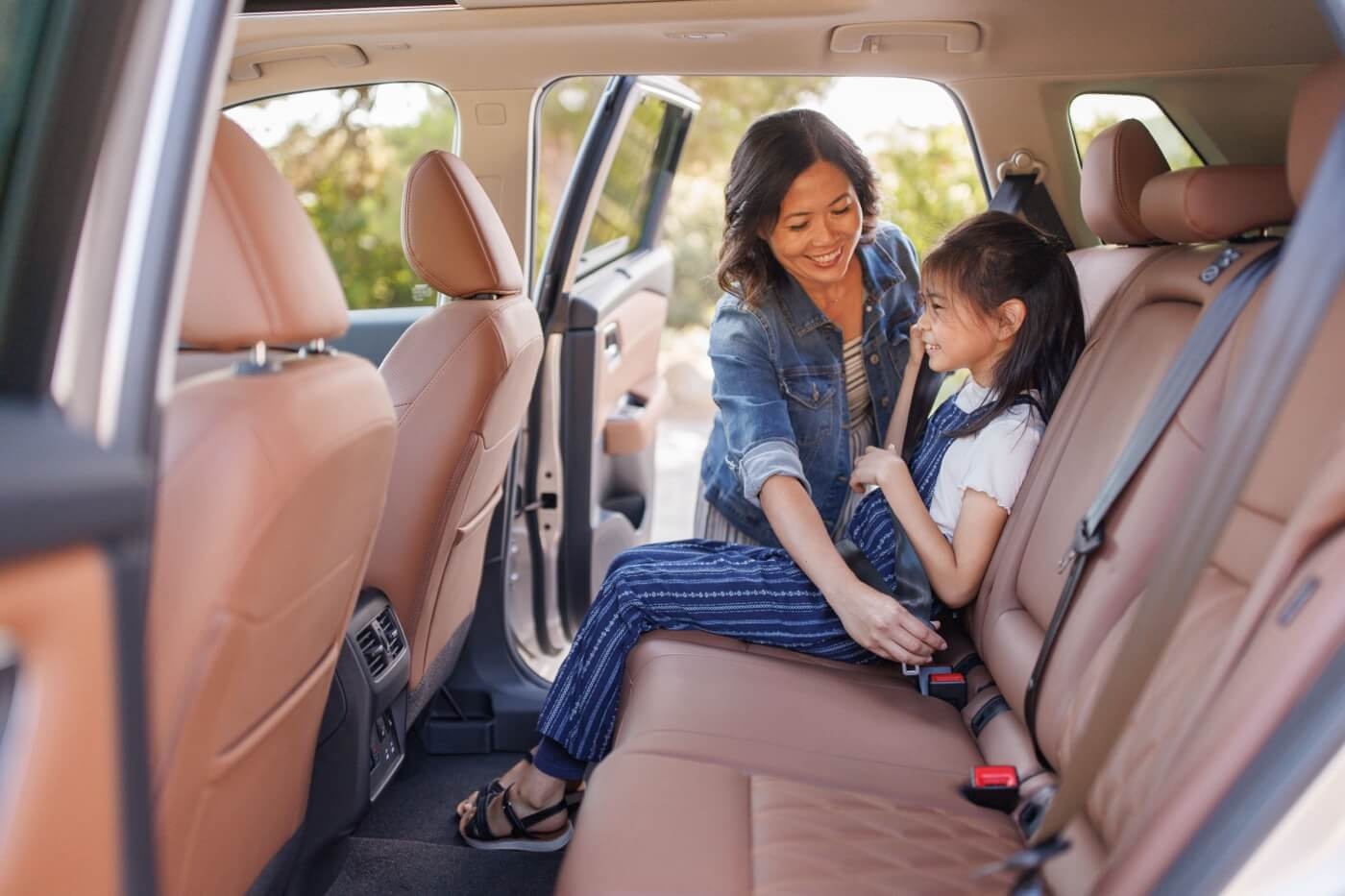 Mère attachant la ceinture sécurité à sa fille à bord du Nissan Rogue 2024.
