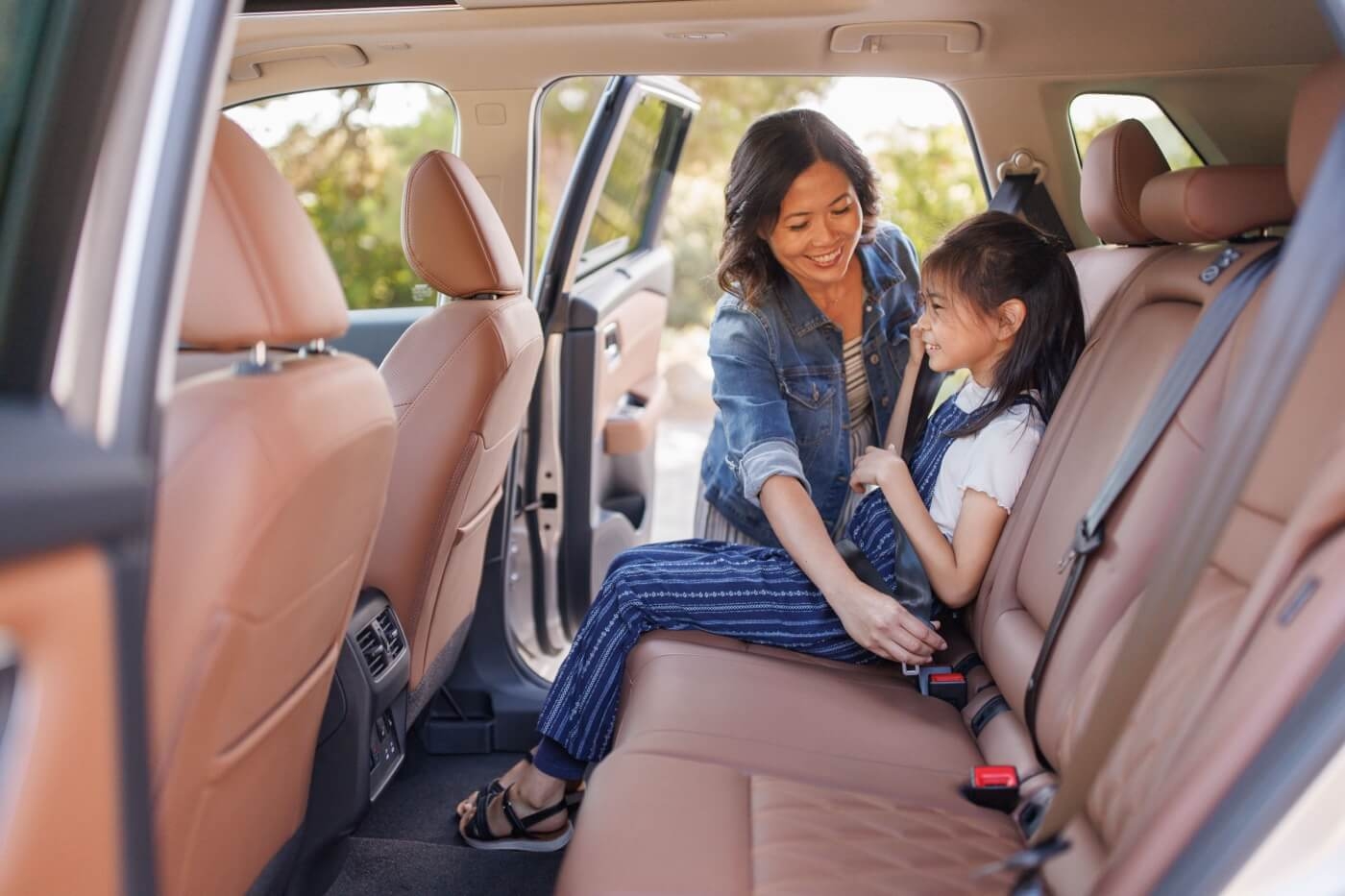 Mère attachant la ceinture sécurité à sa fille à bord du Nissan Rogue 2025.